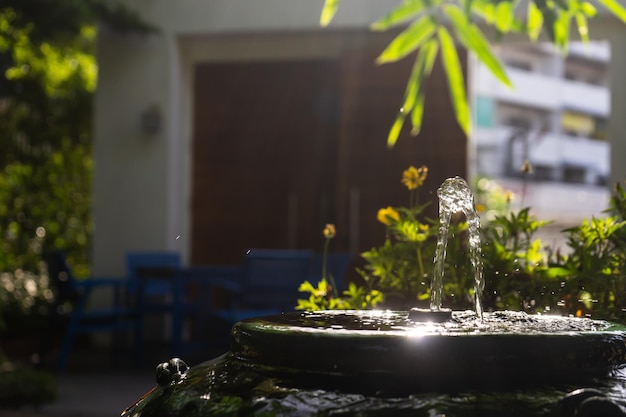 Primo piano a una piccola fontana da un bastoncino di bambù all'interno di un vaso vintage verde decorato in giardino con effetto luce solare