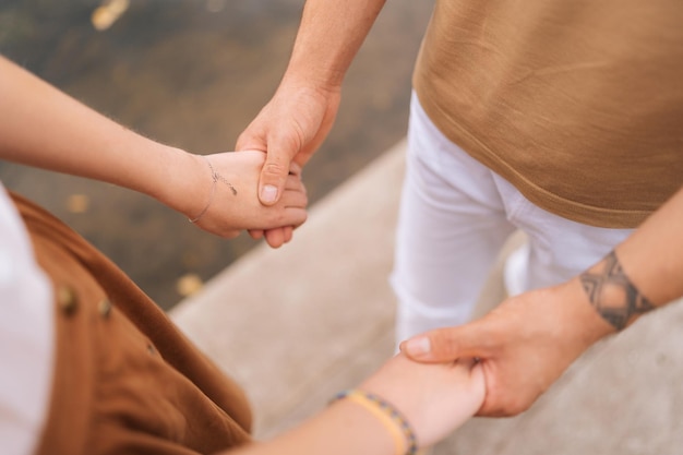 Primo piano ad angolo alto ritagliato colpo di coppia sposata amorevole irriconoscibile in piedi tenendosi per mano all'aperto il giorno d'estate