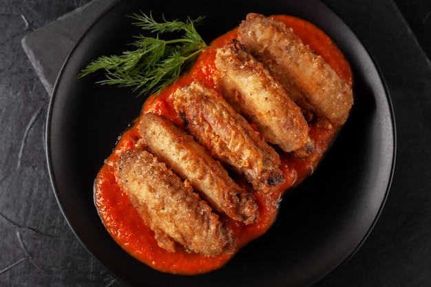 Primo piano appena cucinato delle ali di bufalo con salsa di pomodoro e pomodori