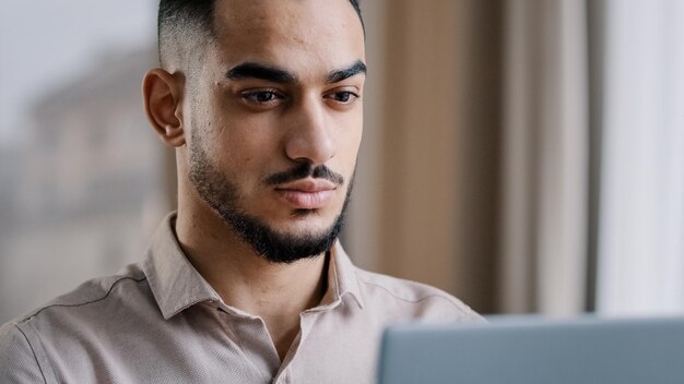 Primo piano arabo uomo d'affari libero professionista web designer digitando SMS e-mail sul computer portatile a casa