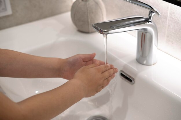 primo piano bambino si lava le mani con acqua igienica