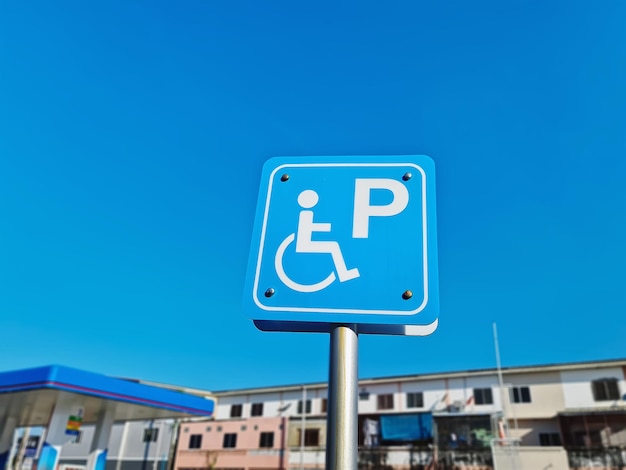 Primo piano bianco parcheggio per disabili segno sull'etichetta blu contro il cielo blu chiaro