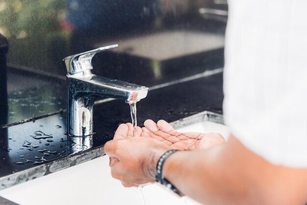 Primo piano che lava le mani dell'uomo di colore sfregando con acqua e sapone nei lavandini per prevenire l'epidemia di igiene del coronavirus per fermare la diffusione del virus, igiene per la pulizia della quarantena concetto COVID-19