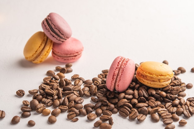 Primo piano dei chicchi di caffè sparsi su una superficie chiara macarons multicolori si trovano sullo spazio superiore