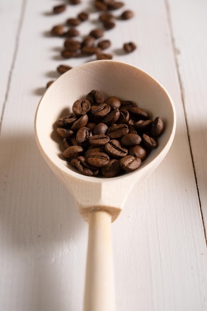 Primo piano dei chicchi di caffè tostati naturali in un cucchiaio di legno