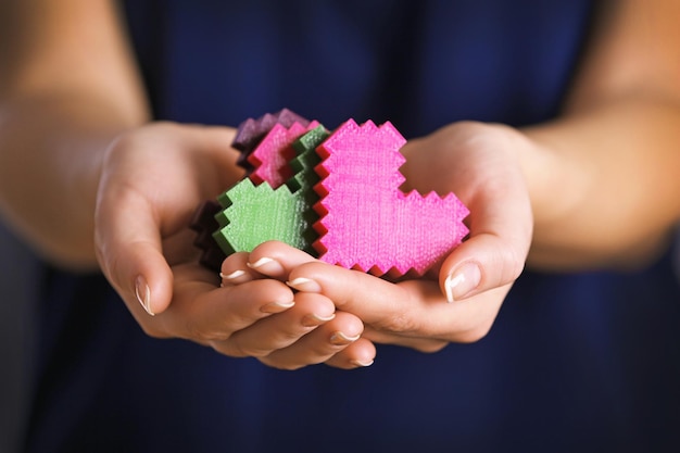 Primo piano dei cuori di puzzle di plastica in mani femminili