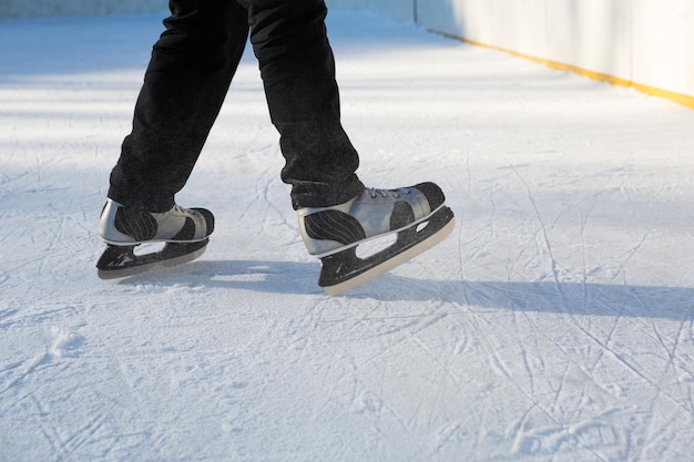 Primo piano dei pattini da ghiaccio degli uomini adulti su ghiaccio in inverno all'aperto in movimento. Rotolare e scivolare in una gelida giornata di sole, sport invernali attivi e stile di vita