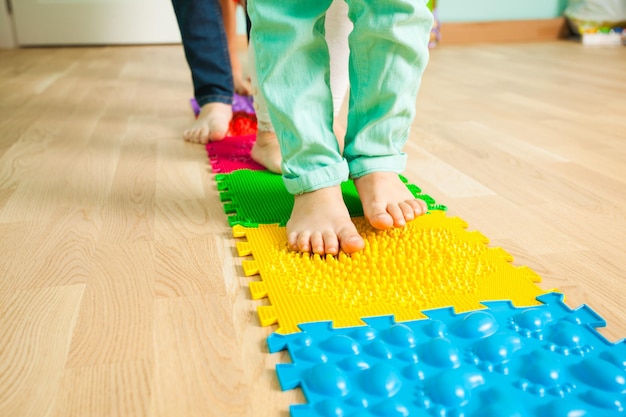 Primo piano dei piedi del bambino mentre si sta in piedi su uno speciale tappetino massaggiante