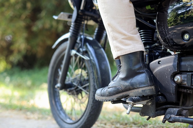 Primo piano dei piedi del motociclista sulla sua moto Moto sul lato del ciclista pronto a ru