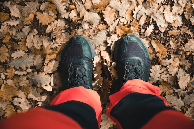 Primo piano dei piedi di un alpinista tra le foglie autunnali cadute