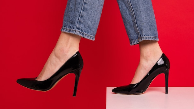 Primo piano dei piedi di una donna in scarpe nere su sfondo rosso