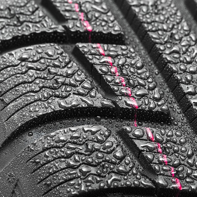 Primo piano dei pneumatici per auto Struttura del profilo della ruota invernale con gocce d'acqua su sfondo bianco
