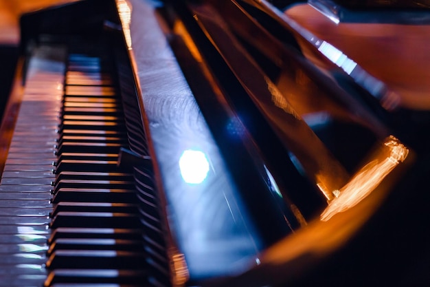 Primo piano dei tasti del pianoforte alla luce delle luci della sera Selezionare la messa a fuoco e la messa a fuoco morbida