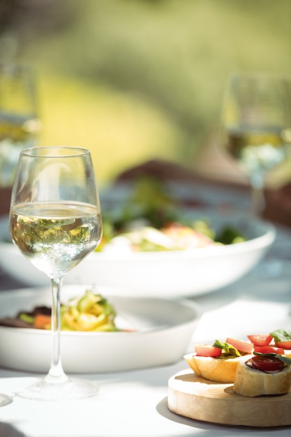 Primo piano del bicchiere di vino e cibo sul tavolo da pranzo