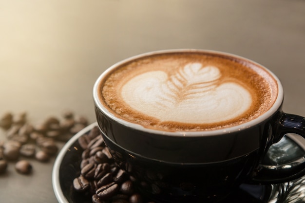 Primo piano del caffè caldo del latte con arte del latte in una tazza nera.