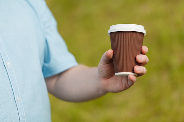 Primo piano del caffè maschio della tenuta della mano da portare via