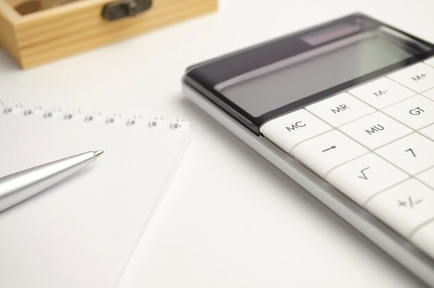 Primo piano del calcolatore dell'estratto conto pila di monete e penna Dipendente di banca che effettua un rapporto Dati statistici Contabilità finanziaria e concetto di contabilità