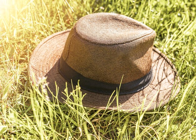 Primo piano del cappello di paglia su erba verde nell'ora legale