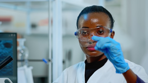 Primo piano del chimico africano che esamina il test del virus in un laboratorio attrezzato. Scienziato africano che lavora con vari batteri, tessuti e campioni di sangue, concetto di ricerca farmaceutica per antibiotici.