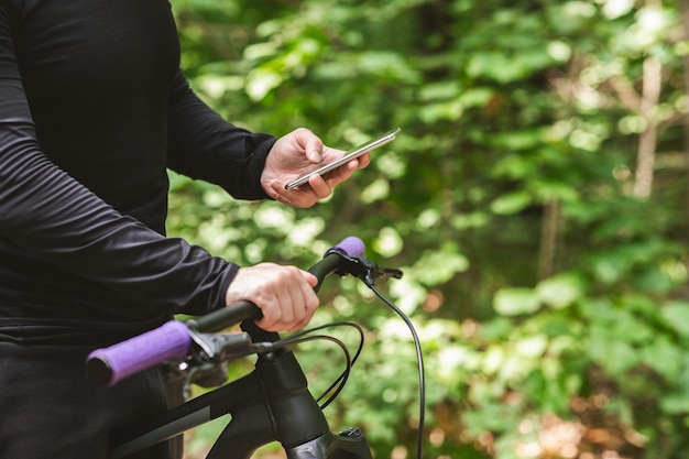 Primo piano del ciclista che tiene la bici usando il telefono