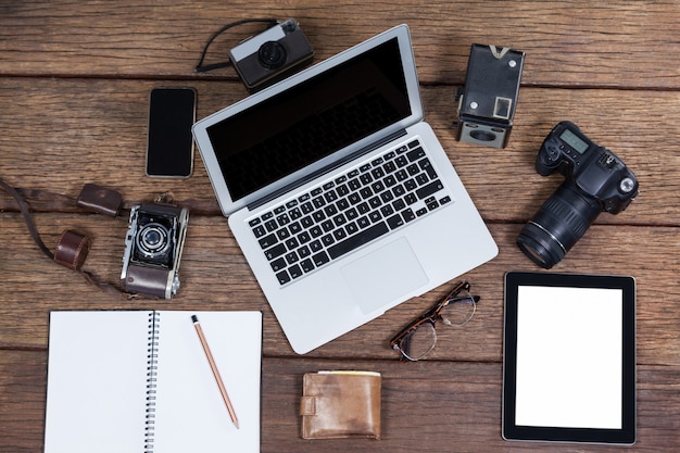 Primo piano del computer portatile con le macchine fotografiche sulla tavola