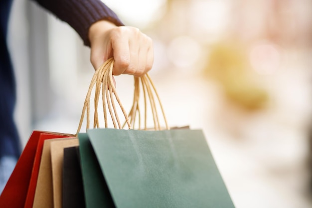 Primo piano del consumismo giovane donna che tiene per mano molti shopping bag nella boutique di moda dopo l'acquisto di regali mentre si cammina lungo la strada con copia spazio godendo di saldi estivi e concetto di persone