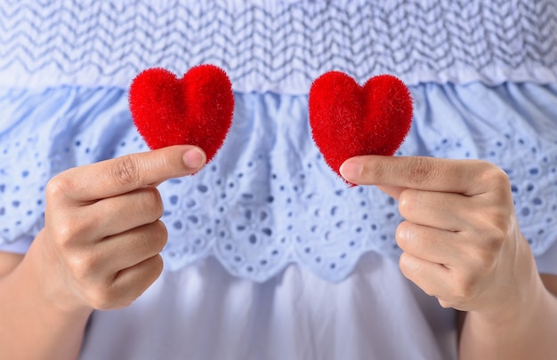 Primo piano del cuore rosso della stretta della mano della donna