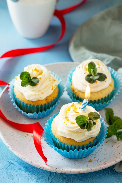 Primo piano del cupcake di compleanno Cupcake colorato con papavero panna montata e scorza d'arancia