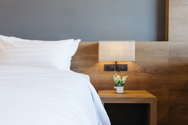 Primo piano del cuscino bianco sulla decorazione del letto con la lampada leggera nell&#39;interno della camera da letto dell&#39;hotel.