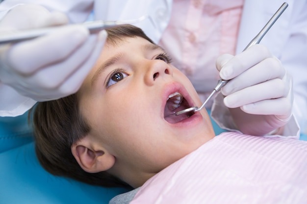 Primo piano del dentista che tiene attrezzature durante l'esame del ragazzo