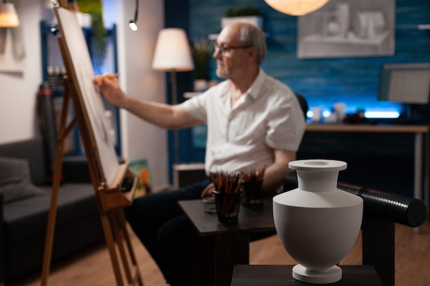 Primo piano del design del vaso bianco sul tavolo con strumenti d'arte