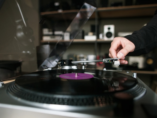 Primo piano del disco in vinile. Negozio di musica retrò. Maschio irriconoscibile che ascolta musica, giradischi moderno