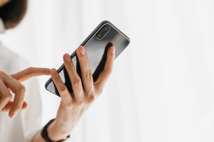 Primo piano del dispositivo dello smartphone della tenuta della mano e messaggio di testo di battitura a macchina sul sociale online.