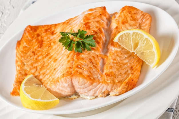 Primo piano del filetto di salmone alla griglia con limone su un piatto bianco vista orizzontale dall'alto