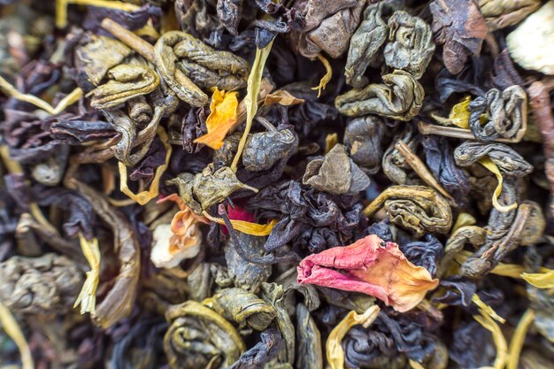 Primo piano del fondo variopinto scuro astratto dei petali di erbe del tè asciutto. Stile di vita sano, bevanda antiossidante naturale, concetto di aromaterapia.