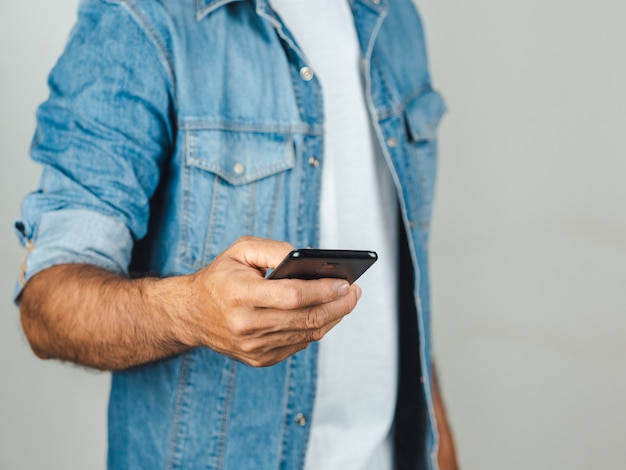 Primo piano del giovane che per mezzo dello smartphone isolato su un bianco