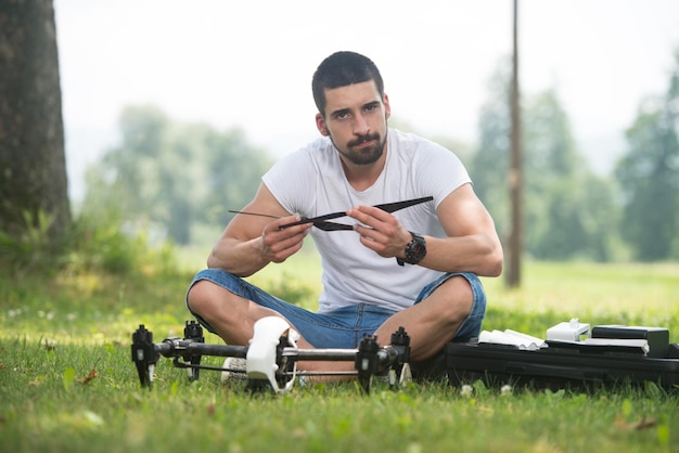 Primo piano del giovane ingegnere che stringe l'elica del drone Uav con strumento manuale nel parco