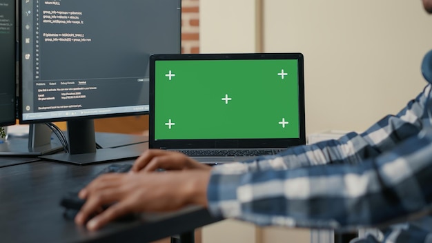 Primo piano del laptop con mockup della chiave cromatica dello schermo verde e mani afroamericane che scrivono codice sulla tastiera del computer. Programmatore che sviluppa software davanti a più schermi che eseguono l'algoritmo ai.