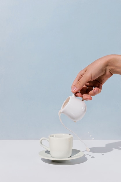 Primo piano del latte di mandorla di versamento della mano della donna nella tazza di caffè