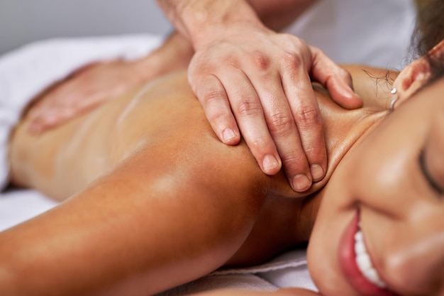 Primo piano del massaggiatore che massaggia la schiena della donna al centro benessere