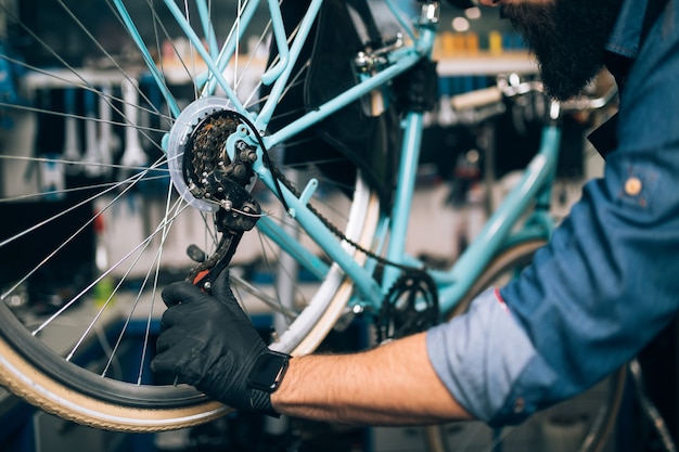 Primo piano del meccanico che ripara le biciclette in un'officina.