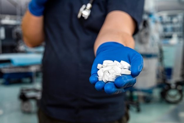 Primo piano del medico in uniforme blu scuro che tiene le pillole con lo stetoscopio