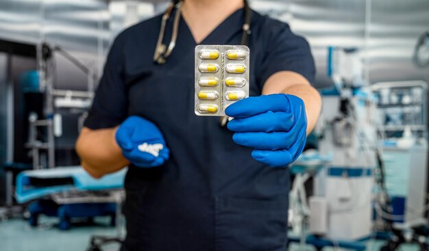 Primo piano del medico in uniforme blu scuro che tiene le pillole con lo stetoscopio