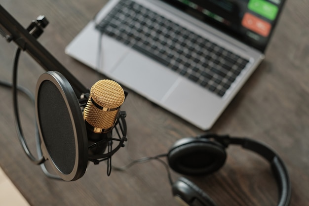 Primo piano del microfono e del laptop con le cuffie sul tavolo in studio di registrazione