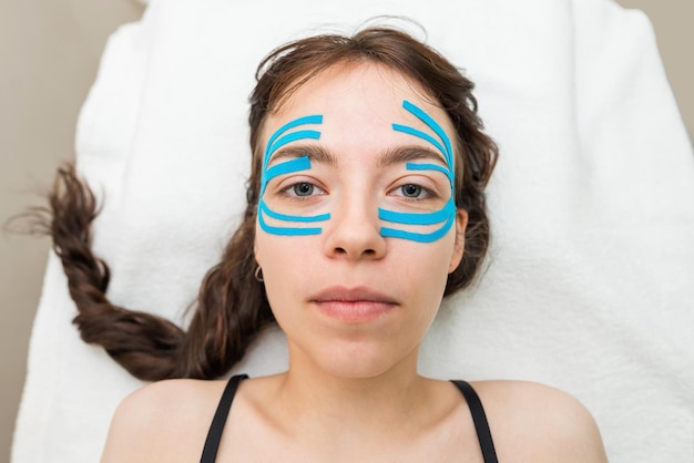Primo piano del nastro facciale del viso di una ragazza con un nastro cosmetico antirughe