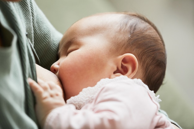 Primo piano del neonato che mangia latte prima di dormire mentre la madre la tiene in braccio