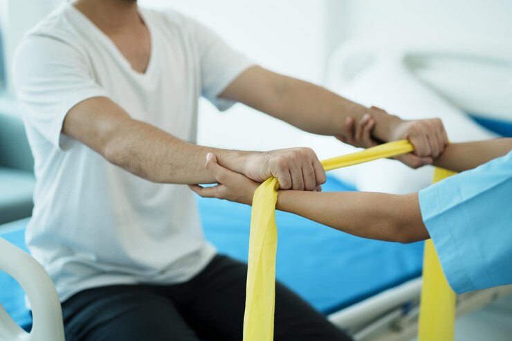 Foto primo piano del paziente che fa esercizi di stretching con una fascia flessibile per esercizi e un fisioterapista
