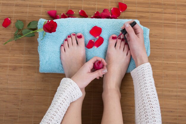 Primo piano del pedicure che applica smalto per unghie