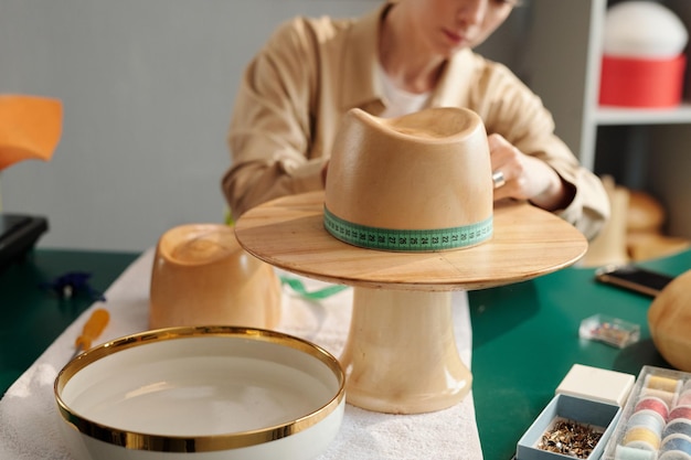 Primo piano del pezzo in lavorazione di legno sotto forma di cappello contro la giovane artigiana