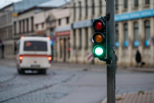 Primo piano del piccolo semaforo del traffico con luce verde sullo sfondo del traffico cittadino